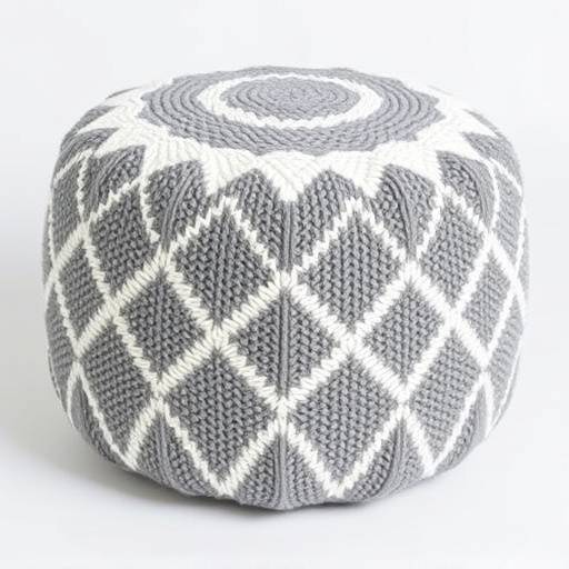 A knitted pouf with a geometric pattern in shades of gray and white.